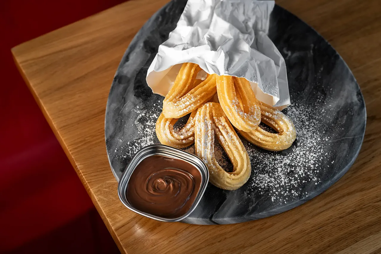 Churros mit Schokoladensoße auf einem Steinteller